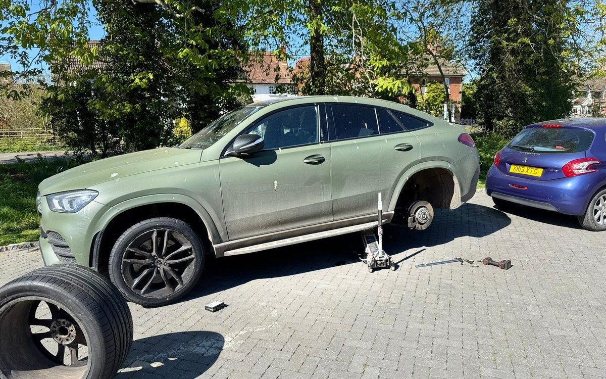 A Mercedes GLE coupe raised on a jack with the wheel off and the replacement on the ground