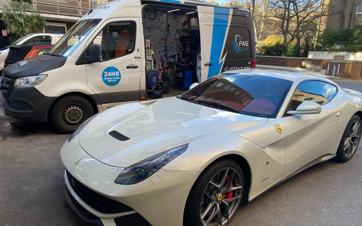 A white Ferrari beside a Fast Tyre van with its side door open