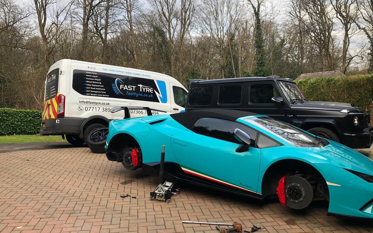 A Lamborghini and a Mercedes G-Class on a driveway, both on jacks, with a Fast Tyre van behind