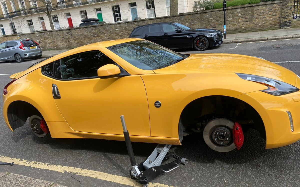 A yellow Nissan 370Z raised on a trolley jack on a London terrace street